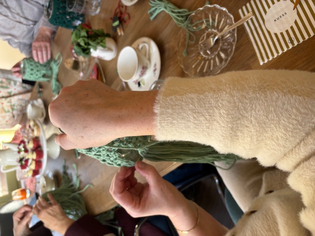 Deelnemers tijdens een macramé workshop aan tafel
